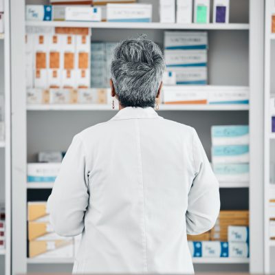 Stock, back and pharmacist at a medicine shelf for healthcare, medical work and service at a pharma